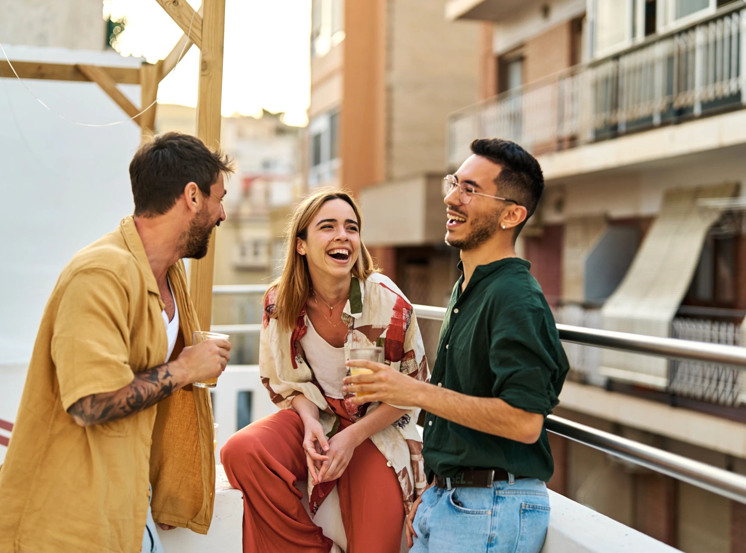 Happy young people having fun during a rooftop party during a summer holiday, standing on the rooftop terrace talking, eating and drinking, love, romance, relationship, flirting and youth culture