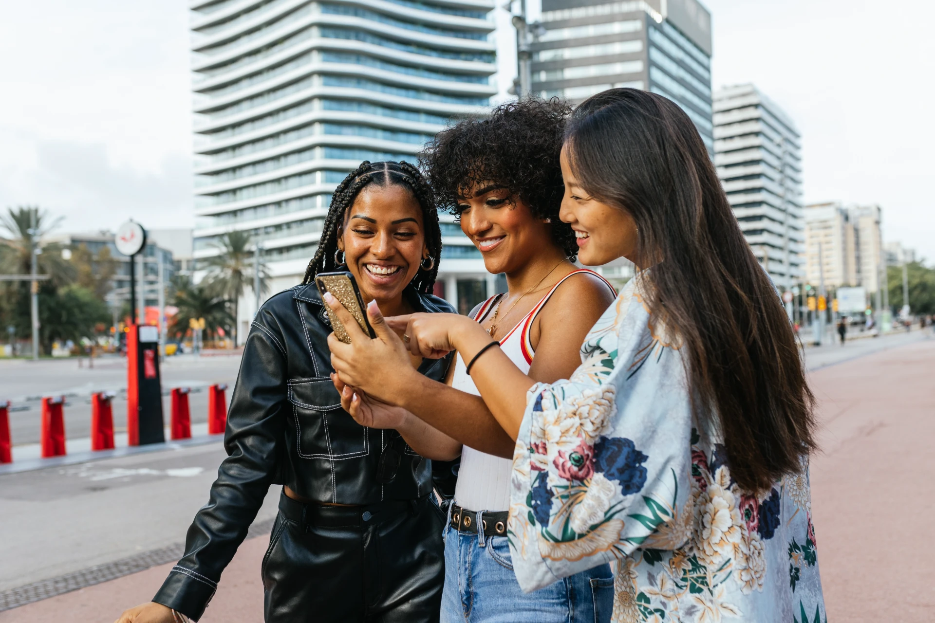 Transgender person and friends using together a mobile phone outdoors