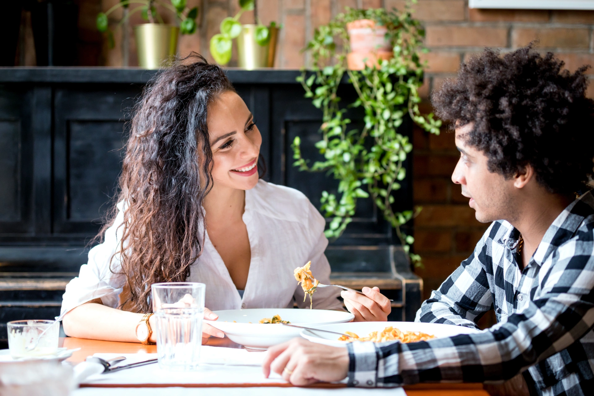 Happy young couple eating lunch together at restaurant, african american people having fun