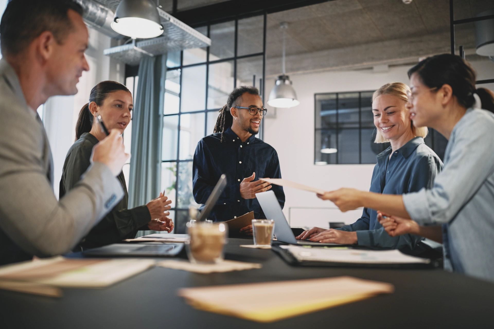 Smiling young businessman talking with a group of colleagues during a staff meeting in an office boardroom