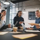 Smiling young businessman talking with a group of colleagues during a staff meeting in an office boardroom